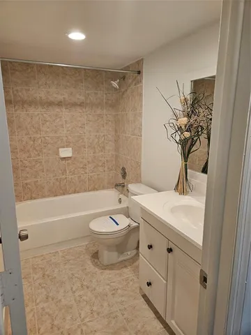 a bathroom with a toilet a sink a mirror a bathtub and vanity