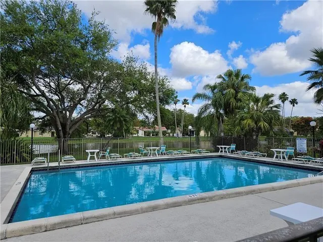 a view of swimming pool with outdoor seating and trees in the background