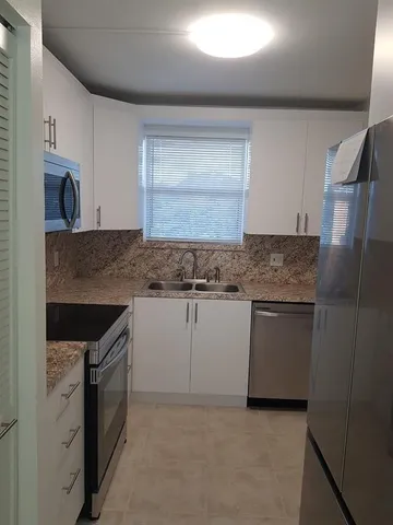 a kitchen with granite countertop cabinets stainless steel appliances and a sink