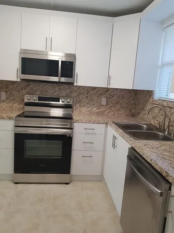 a kitchen with granite countertop white cabinets and stainless steel appliances
