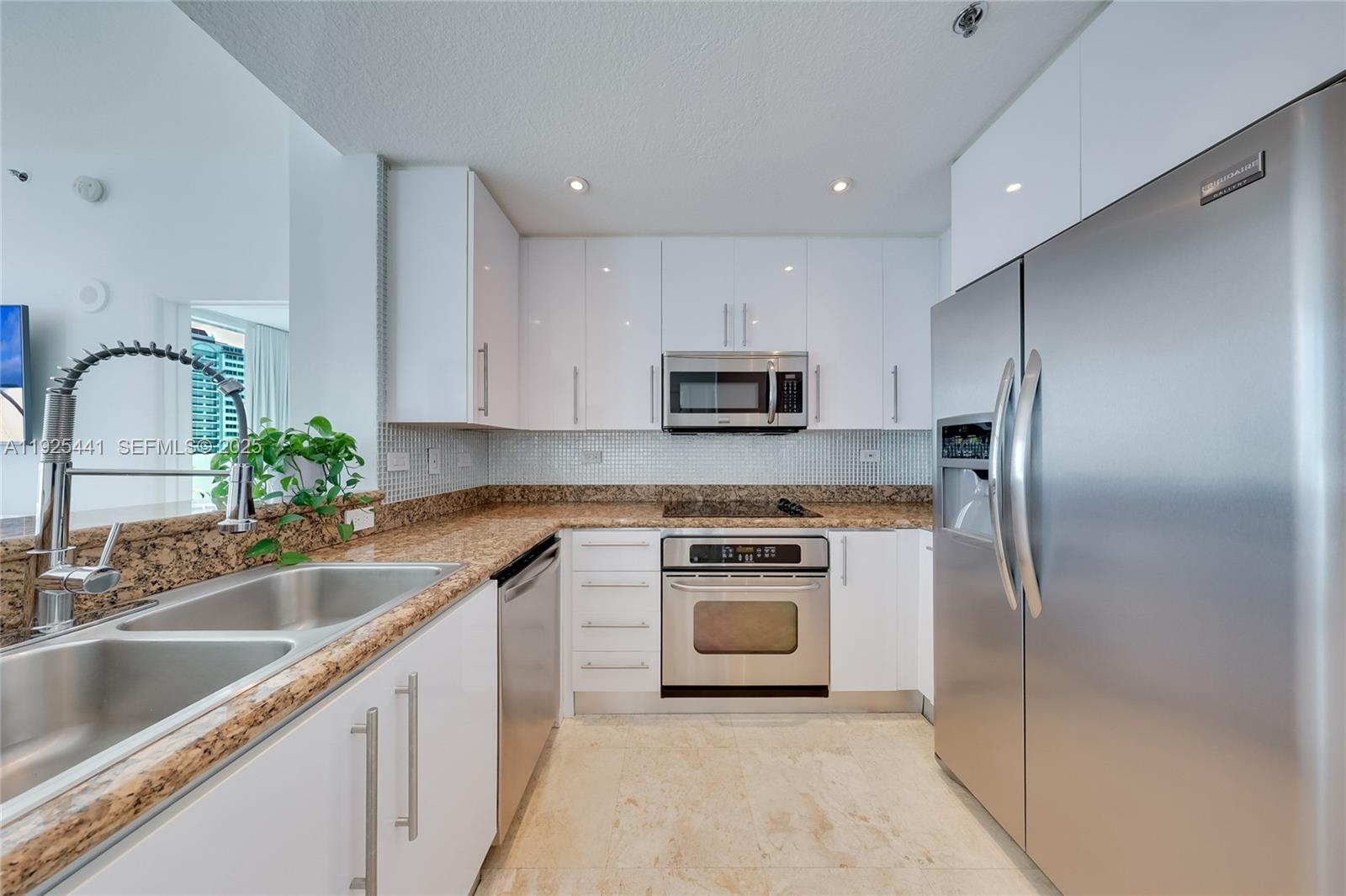 6515 Collins Avenue, Unit 605 Miami Beach, FL 33141 - Photo 7 of 18 a kitchen with kitchen island a sink stainless steel appliances and cabinets