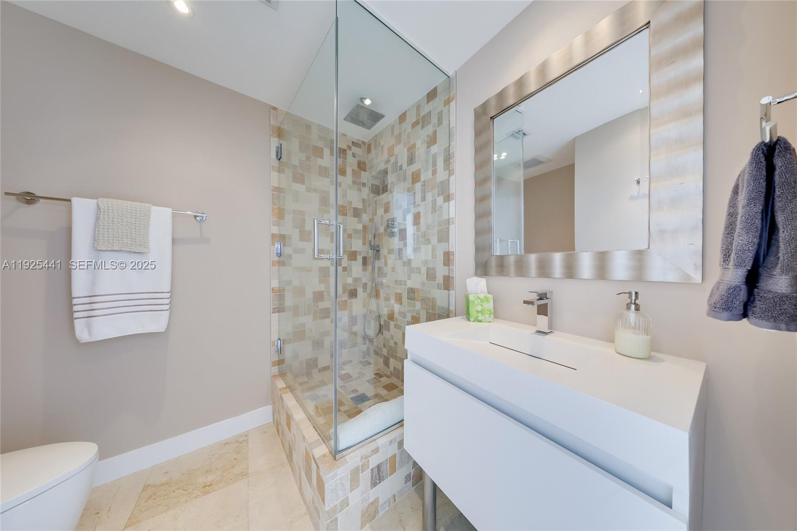 6515 Collins Avenue, Unit 605 Miami Beach, FL 33141 - Photo 8 of 18 a bathroom with a sink a toilet a mirror and shower