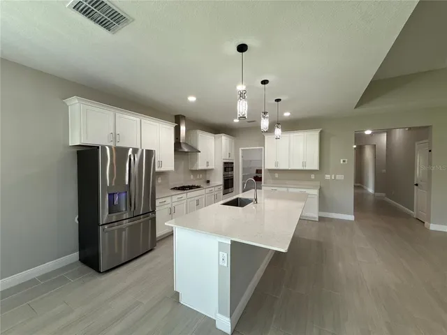 a kitchen with stainless steel appliances kitchen island granite countertop a refrigerator a stove a sink and a refrigerator