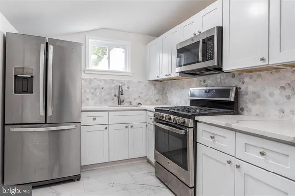 a kitchen with stainless steel appliances granite countertop white cabinets granite counter tops and a window