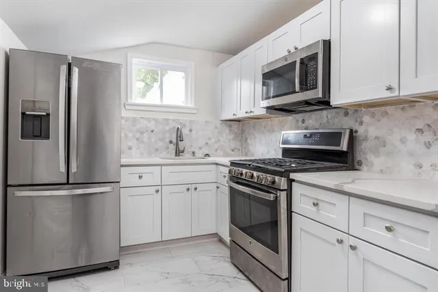 a kitchen with stainless steel appliances granite countertop white cabinets granite counter tops and a window