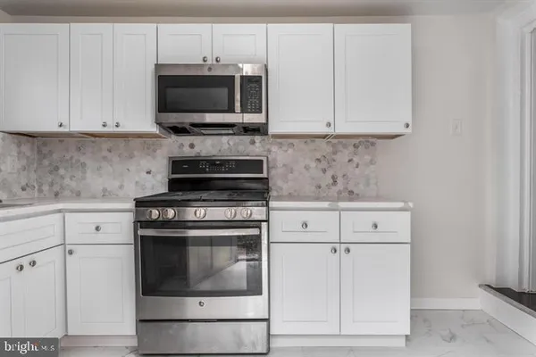 a kitchen with granite countertop white cabinets and stainless steel appliances