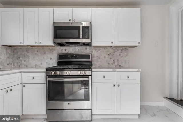 a kitchen with granite countertop white cabinets and stainless steel appliances