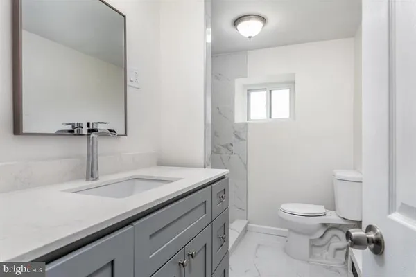 a bathroom with a granite countertop sink a toilet and a mirror