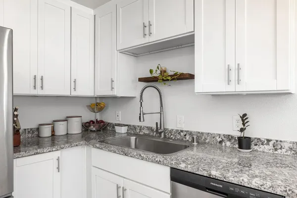 a kitchen with granite countertop white cabinets and a sink