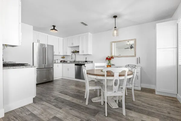 a kitchen with stainless steel appliances a dining table chairs refrigerator and cabinets