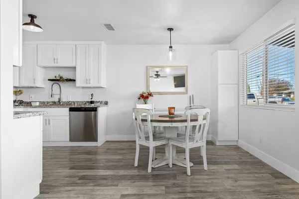 a kitchen with stainless steel appliances kitchen island granite countertop a wooden floor and white cabinets