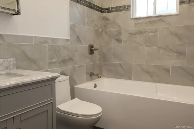 a bathroom with a granite countertop toilet a sink and bathtub