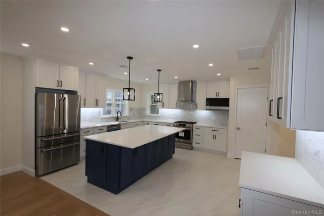 a large kitchen with stainless steel appliances a sink a stove a refrigerator and cabinets