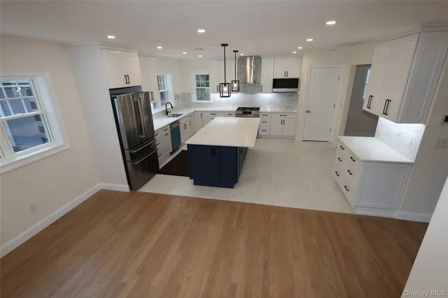 a large white kitchen with wooden floors and stainless steel appliances