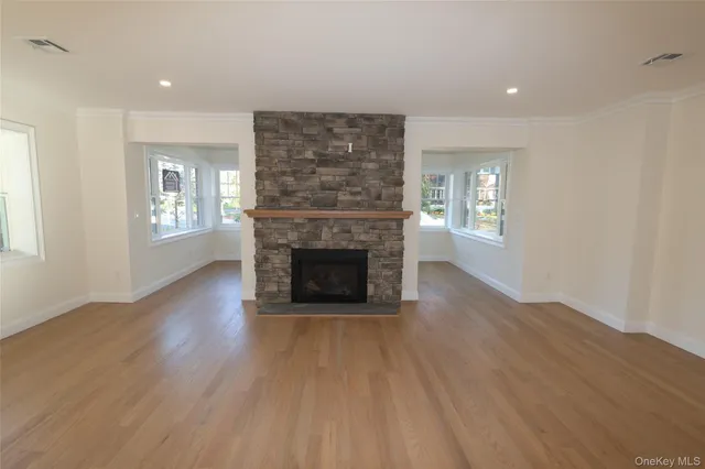 an empty room with windows a fireplace and wooden floor
