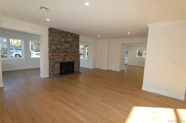 an empty room with wooden floor fireplace and windows