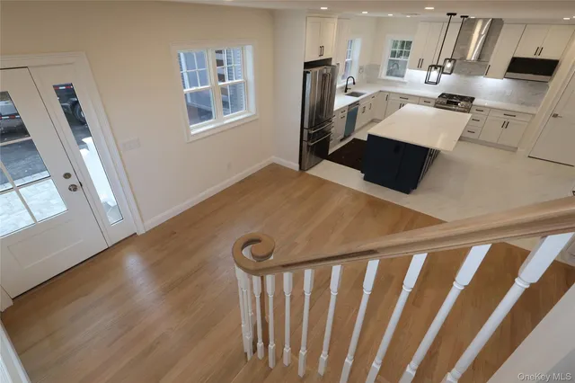 a kitchen with stainless steel appliances a refrigerator a sink a stove and white cabinets