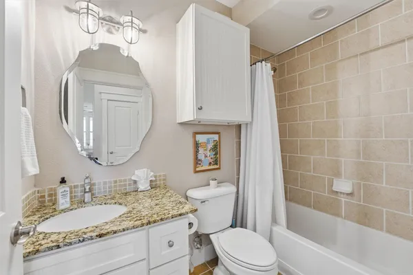 a bathroom with a granite countertop sink a toilet and bathtub
