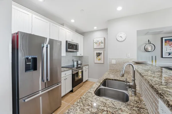 a kitchen with stainless steel appliances granite countertop a refrigerator sink and stove