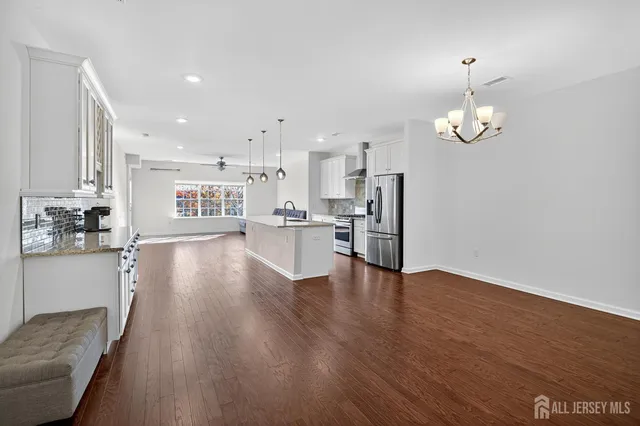 a living room with stainless steel appliances granite countertop furniture wooden floor and a kitchen view