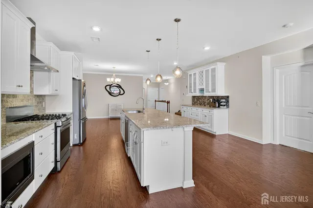 a large kitchen with stainless steel appliances kitchen island a large counter top and a wooden floors