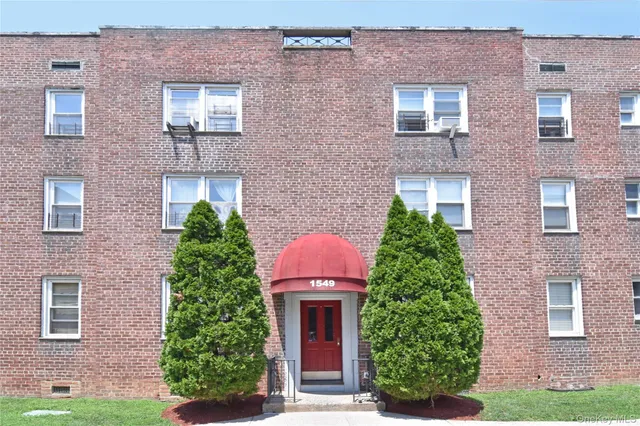 front view of a brick house with a yard and plants