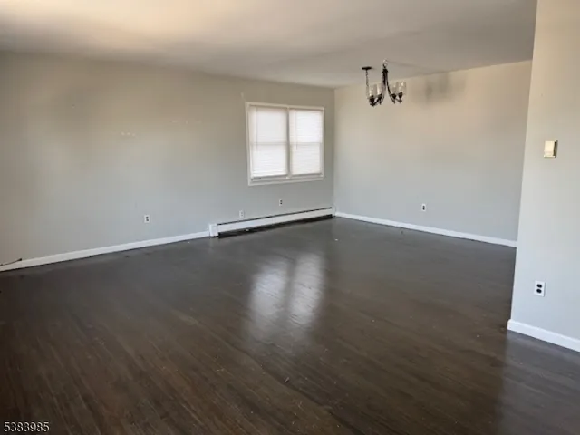 a view of an empty room with wooden floor and window
