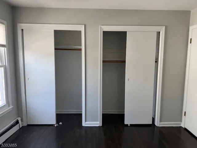 an empty room with wooden floor closet and windows