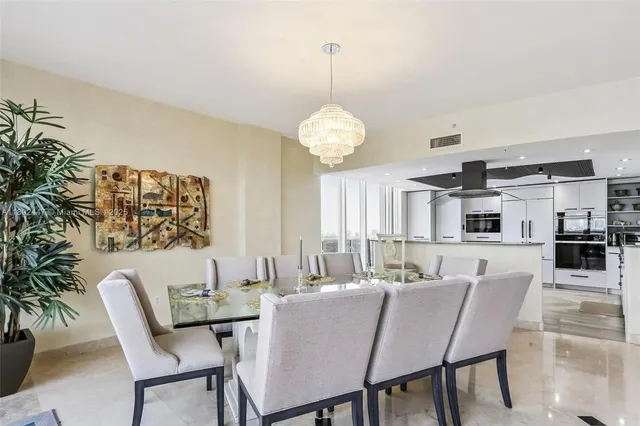 a dining room with furniture a chandelier and large windows