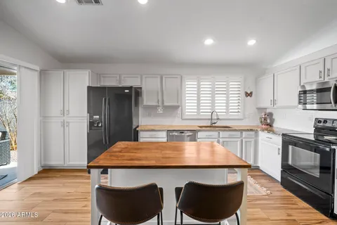 a kitchen with a table chairs a refrigerator and wooden floor
