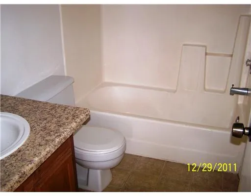 a bathroom with a granite countertop sink a toilet and bathtub