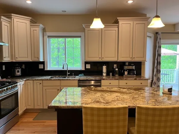 a kitchen with kitchen island granite countertop a stove a sink and a granite counter tops