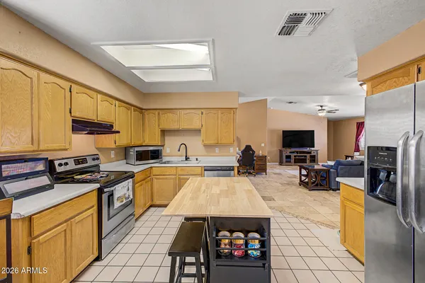 a kitchen with stainless steel appliances a stove a sink a oven a refrigerator cabinets and living room view