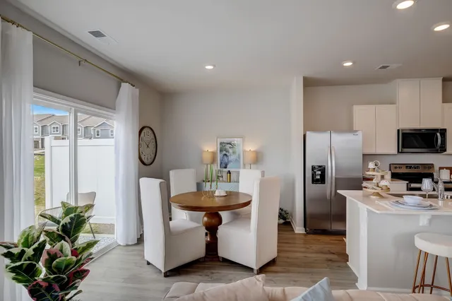 a kitchen with stainless steel appliances a dining table chairs stove and refrigerator