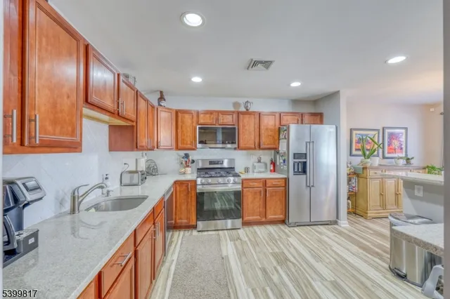 a kitchen with stainless steel appliances granite countertop a refrigerator a sink dishwasher stove and oven