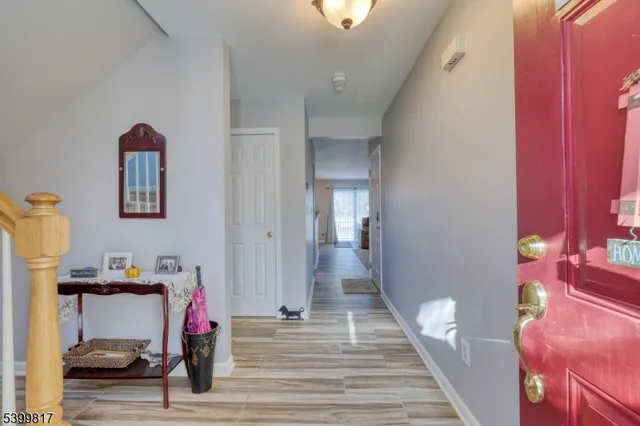 a view of a hallway to a livingroom with wooden floor and furniture