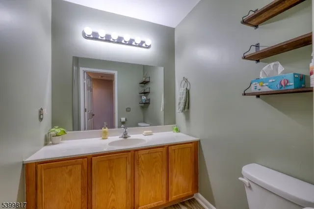 a bathroom with a granite countertop sink a toilet and a mirror