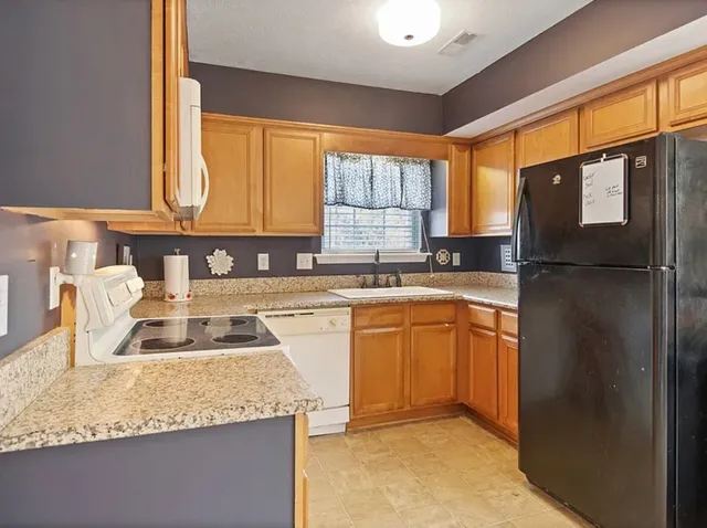 a kitchen with granite countertop a sink window and refrigerator