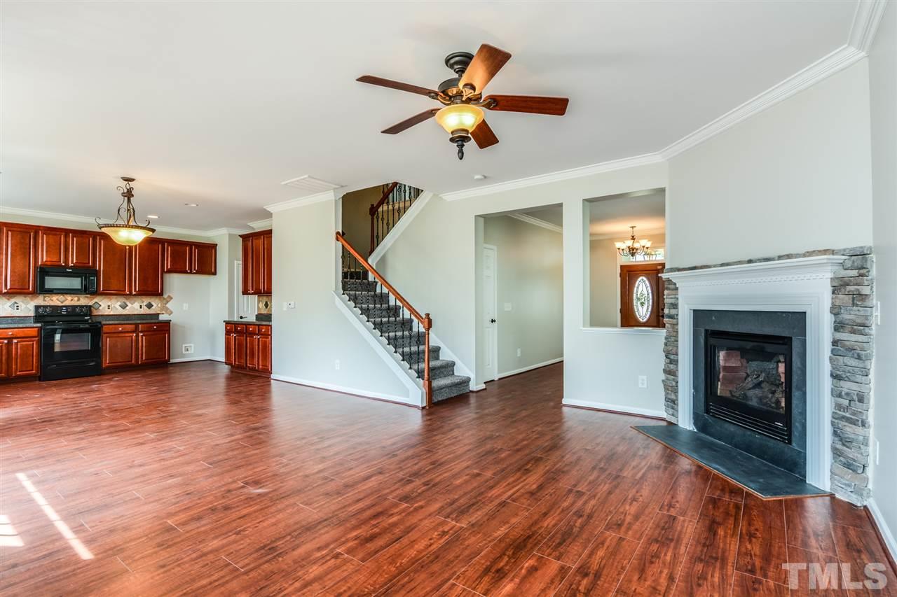 136 Ryder Cup Circle Raleigh, NC 27603 - Photo 7 of 17 a view of a livingroom with a fireplace a ceiling fan and a kitchen view