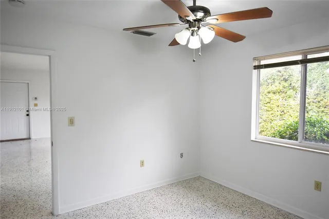 an empty room with a window and a fan