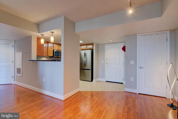 a view of an empty room with wooden floor and a bathroom
