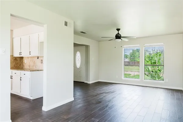a view of an empty room with wooden floor and a window