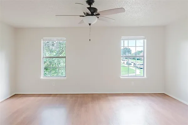 an empty room with a window and a fan
