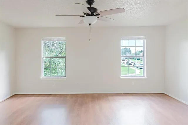 an empty room with a window and a fan