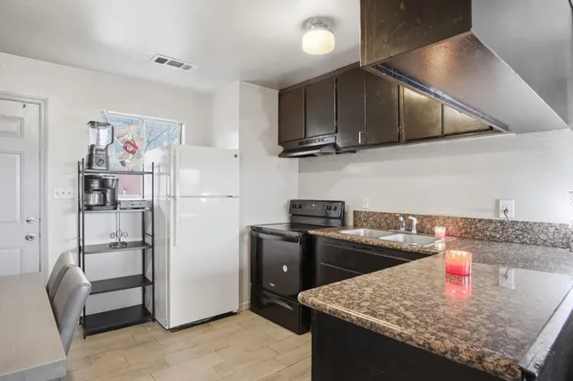 a kitchen with stainless steel appliances granite countertop a refrigerator a stove and a sink with wooden floor