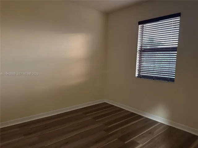 a view of a room that has wooden floor and a window