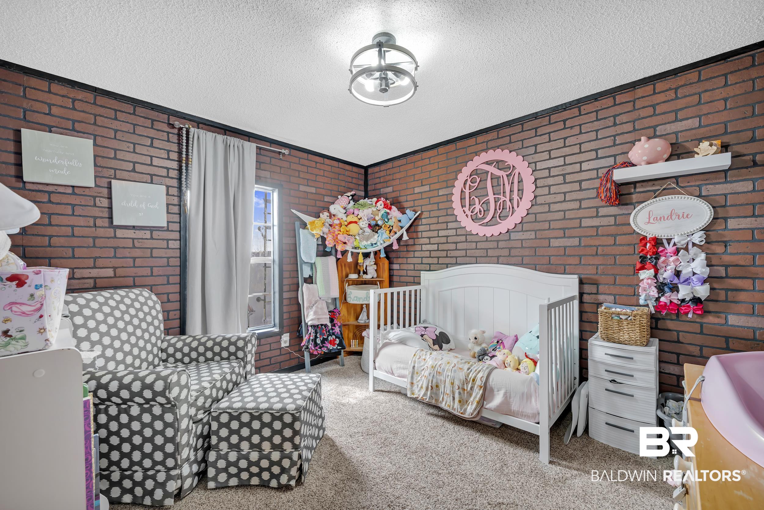 22823 Lanier Road Robertsdale, AL 36567 - Photo 32 of 46 Bedroom featuring brick wall, carpet, and a textured ceiling