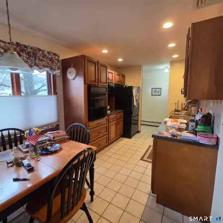 a kitchen with stainless steel appliances kitchen island granite countertop a table chairs and a refrigerator