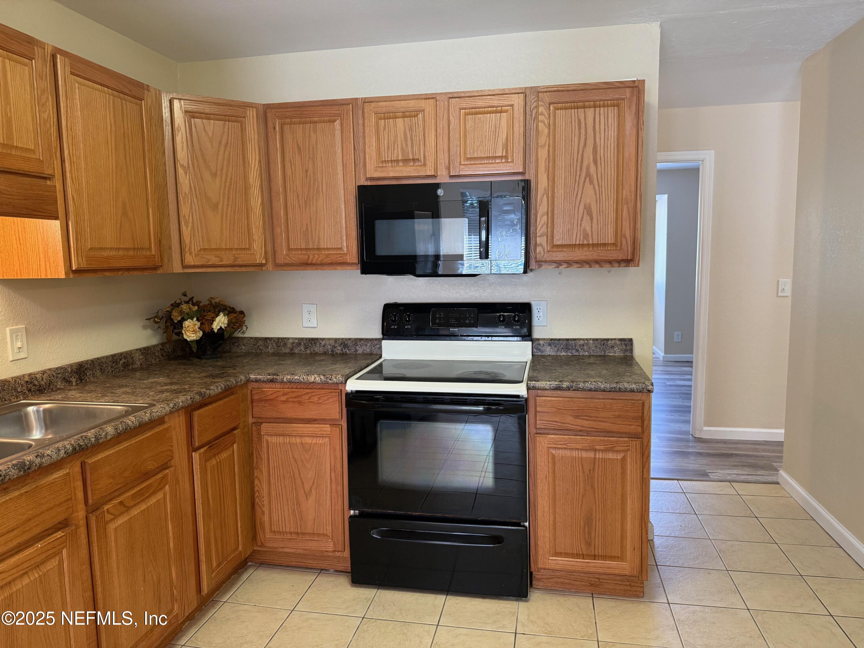 8880 Old Kings Road South, Unit 6 Jacksonville, FL 32257 - Photo 8 of 27 a kitchen with granite countertop a stove a sink and a microwave