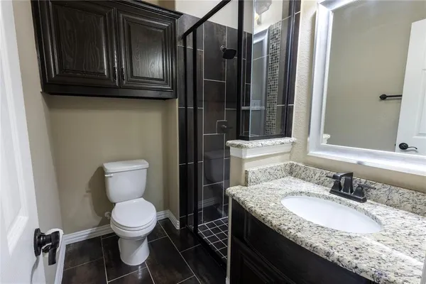 a bathroom with a granite countertop toilet sink and mirror